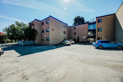 A parking lot in front of a building with a blue car parked.
