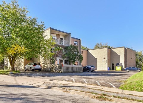 A sunny day at a residential area with cars parked and buildings in the background.