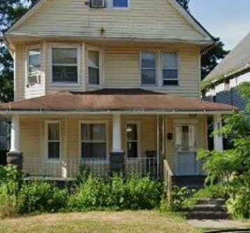A yellow house with a porch and a front door.