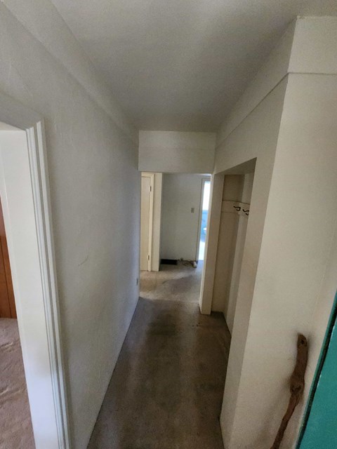 A long white hallway with a door on the left and a door on the right.