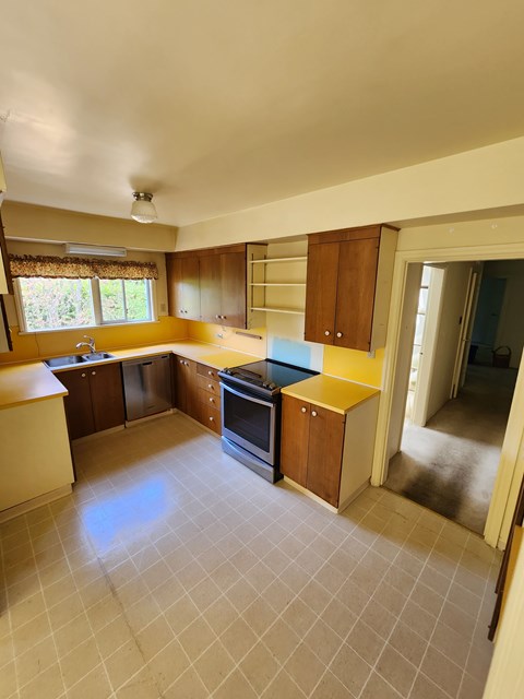 A kitchen with a yellow counter top and a black stove.