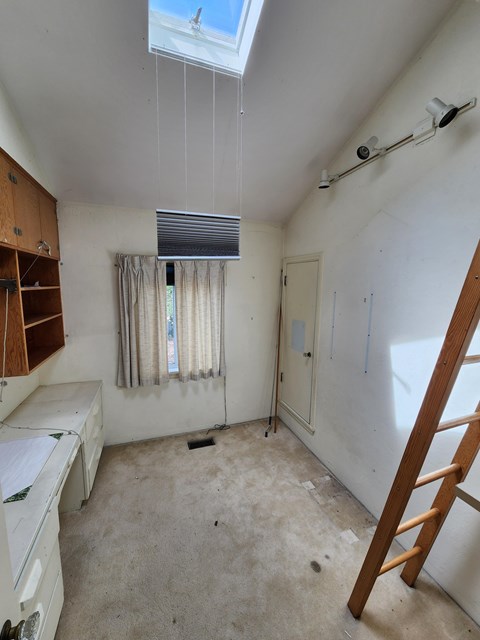 A room with a ladder and a window with curtains.