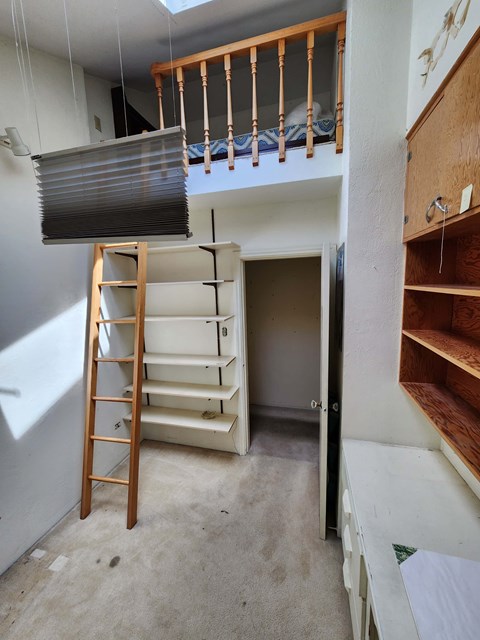 A room with a wooden ladder and a white wall.