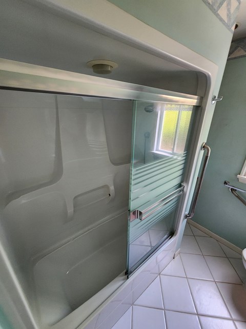 A white shower stall with a glass door and a window.