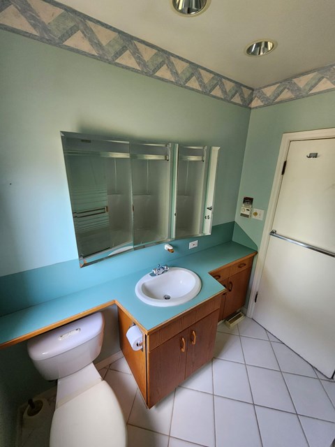 A bathroom with a sink, toilet and mirror.