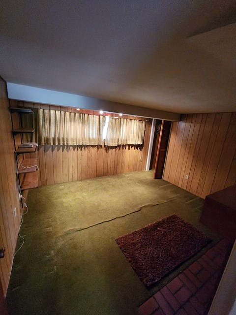 A room with a rug on the floor and a window with curtains.