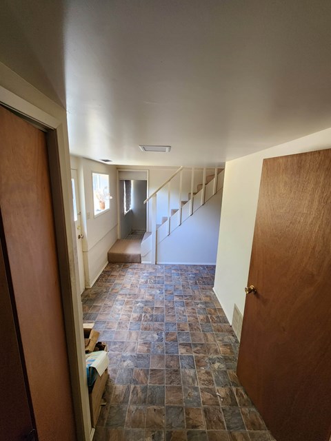 A hallway with a tiled floor and a staircase.