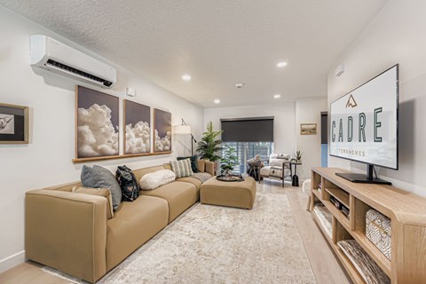A living room with a large couch and a flat screen TV mounted on the wall.