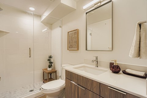 A bathroom with a white sink, toilet, and a mirror.
