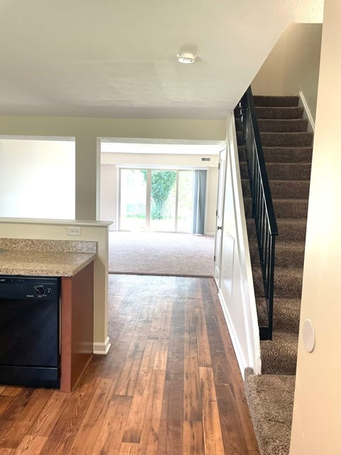 A kitchen with a dishwasher and a staircase.