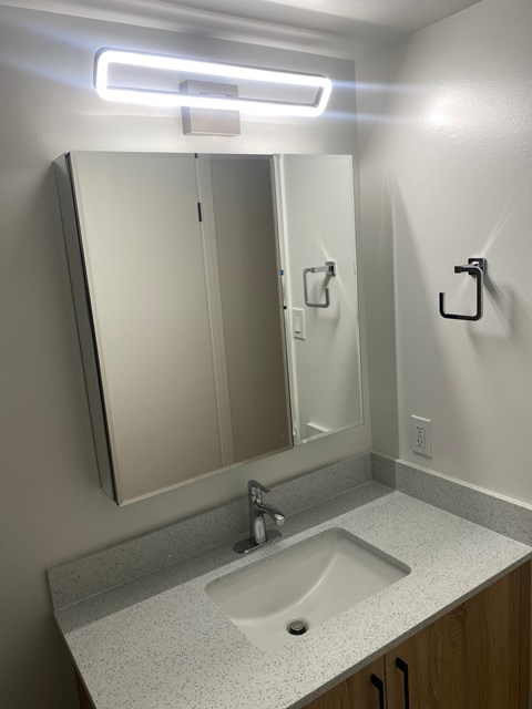A bathroom with a sink, mirror, and light.