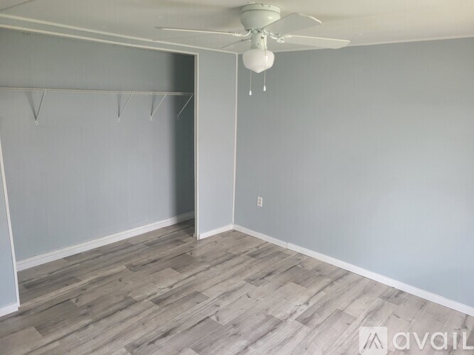 A room with a ceiling fan and a doorway leading to another room.