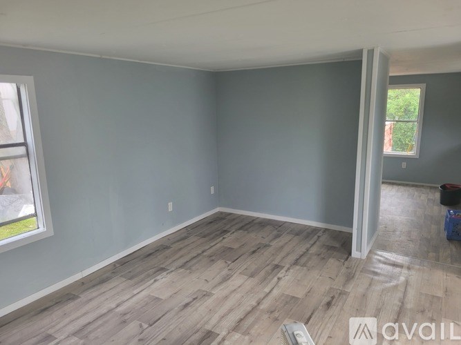 A room with light grey walls and wooden flooring is available for rent.
