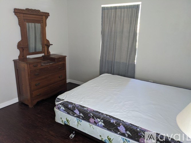 A bedroom with a bed, wooden dresser, and a mirror.