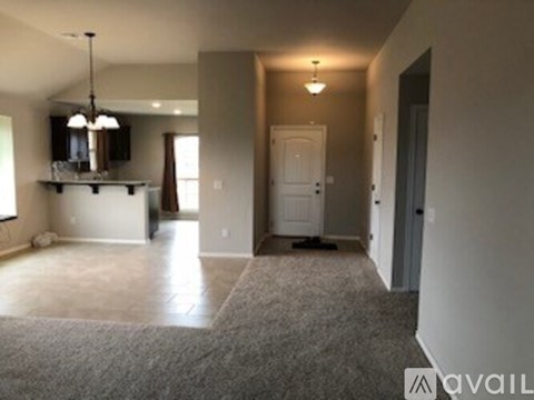 A spacious living room with a grey carpet and a white door.
