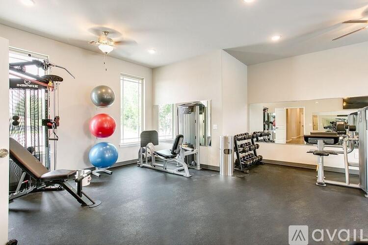 A gym with a variety of equipment including a bench press, a leg press, a squat rack, a mirror, and a rowing machine.