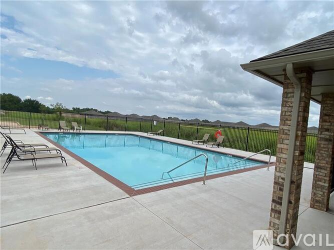 A pool surrounded by a black fence with a person sitting on a chair.
