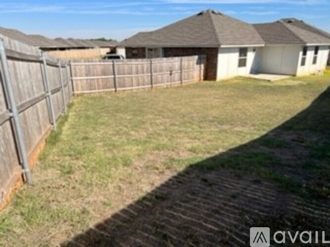 A grassy area with a wooden fence and a house in the background.