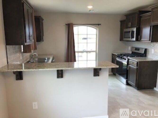 A kitchen with dark brown cabinets and a granite countertop.