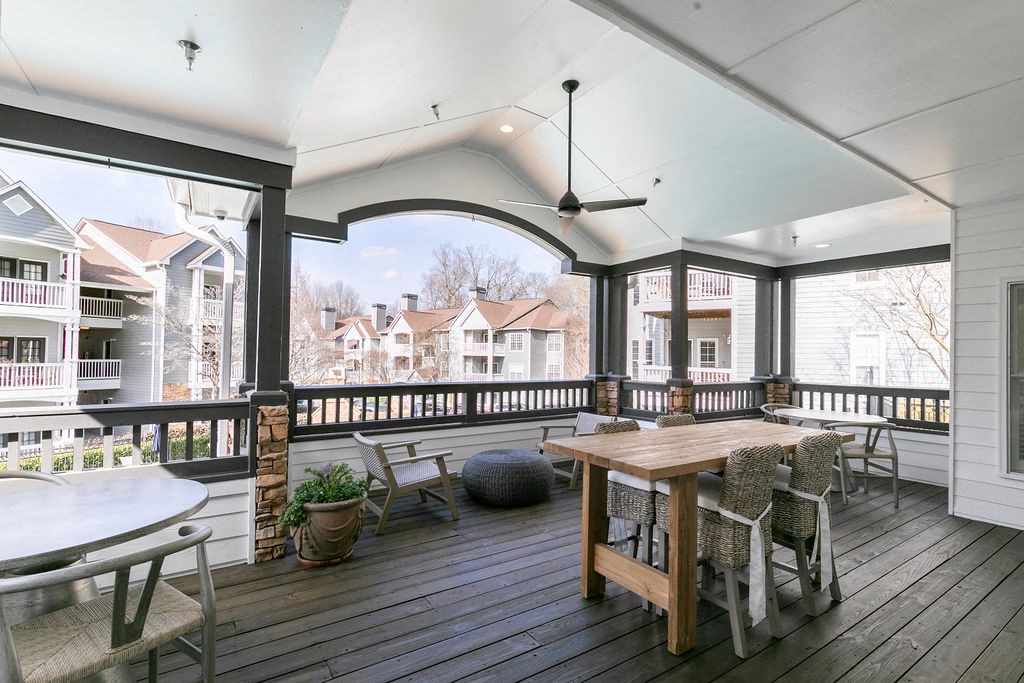 a covered porch with a table and chairs and large windows