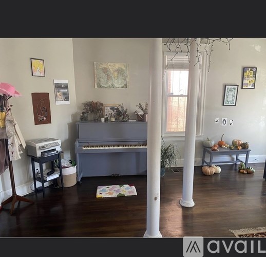 A room with a piano, a printer, and a pumpkin on a table.