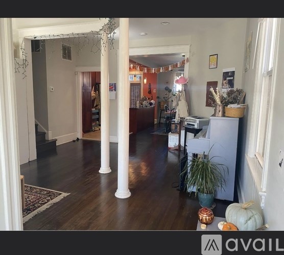 A living room with a white column and a wooden floor.
