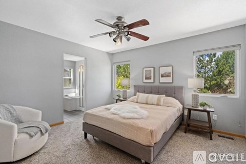 A bedroom with a bed, chair, and ceiling fan.