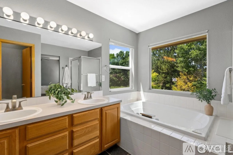 A bathroom with a large tub and a window overlooking trees.