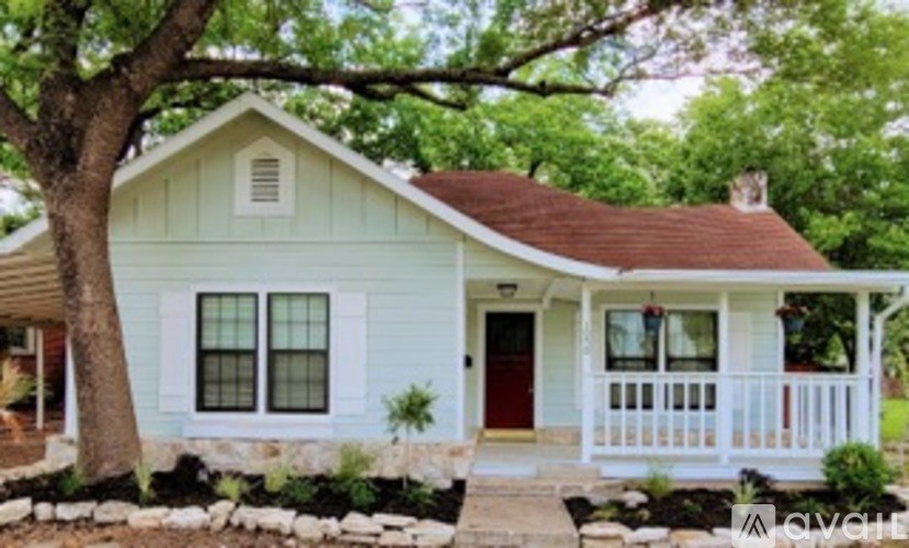 A small house with a red door and a porch.
