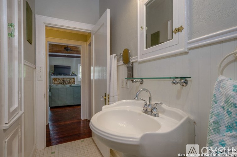 A white bathroom sink with a gold faucet.
