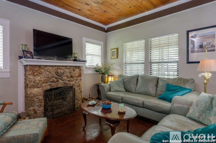 A living room with a stone fireplace and a grey couch.