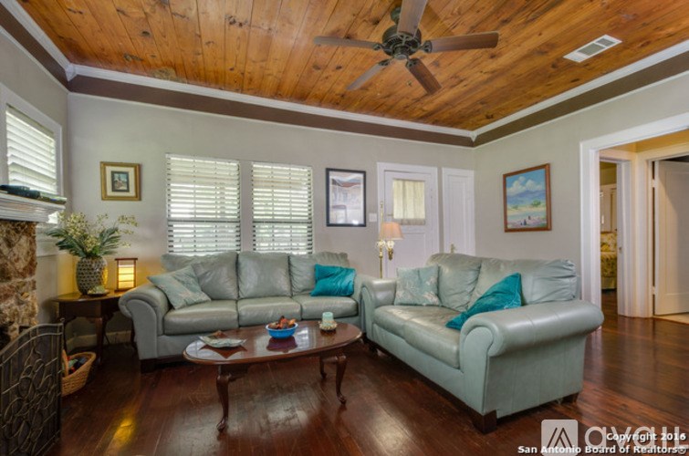 A living room with a wooden ceiling and a fireplace.