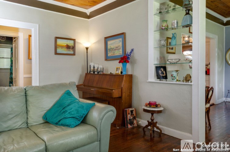A living room with a couch, a table, a lamp, and a piano.