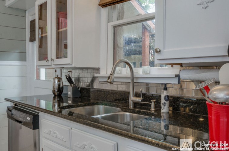 A kitchen with a black granite countertop and white cabinets.