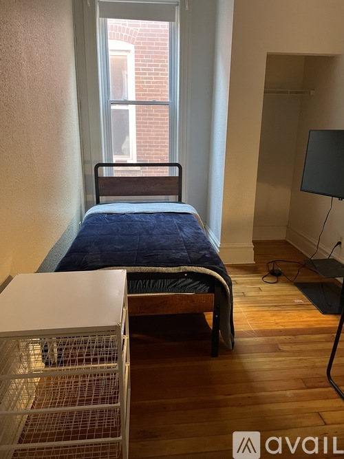 A bedroom with a bed, a chair, and a window.