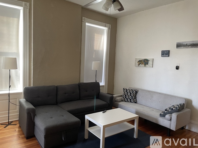 A living room with a grey couch, a white coffee table, and a small grey ottoman.