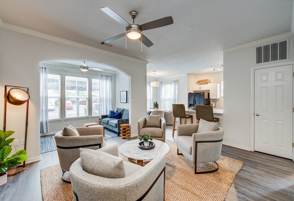 a living room with couches and chairs and a ceiling fan
