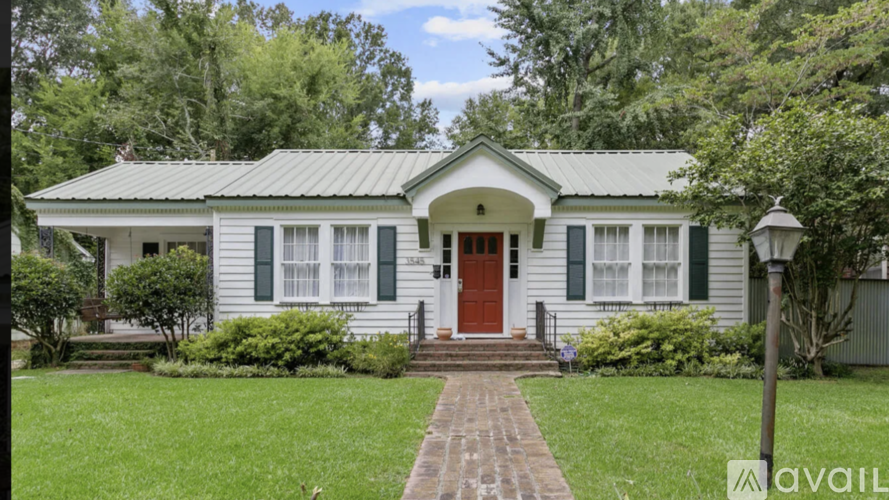 A white house with a red door and green shutters.