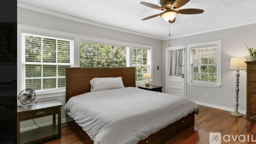 A bedroom with a bed, a ceiling fan, and a window with blinds.