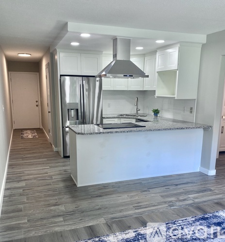 A modern kitchen with a white island and stainless steel appliances.