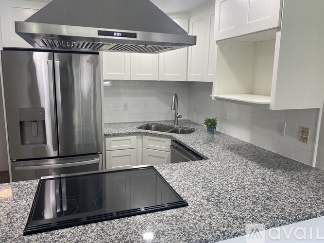 A kitchen with granite countertops and a stainless steel refrigerator.