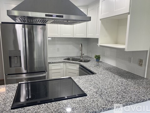 A kitchen with granite countertops and a stainless steel refrigerator.