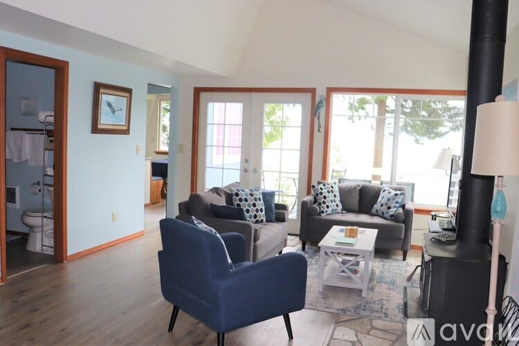 A living room with a blue chair and a black fireplace.