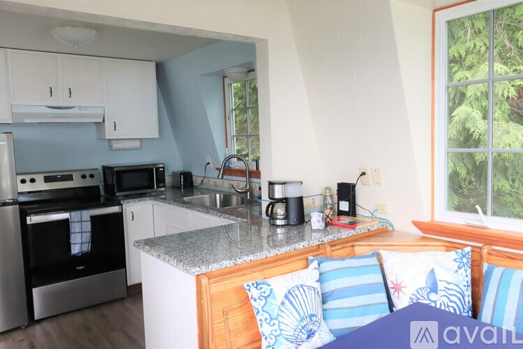 A kitchen with a stove top oven and microwave, a sink, and a window with a view of trees.