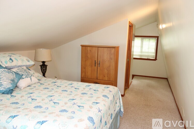 A bedroom with a bed, a lamp, a wooden wardrobe and a window.