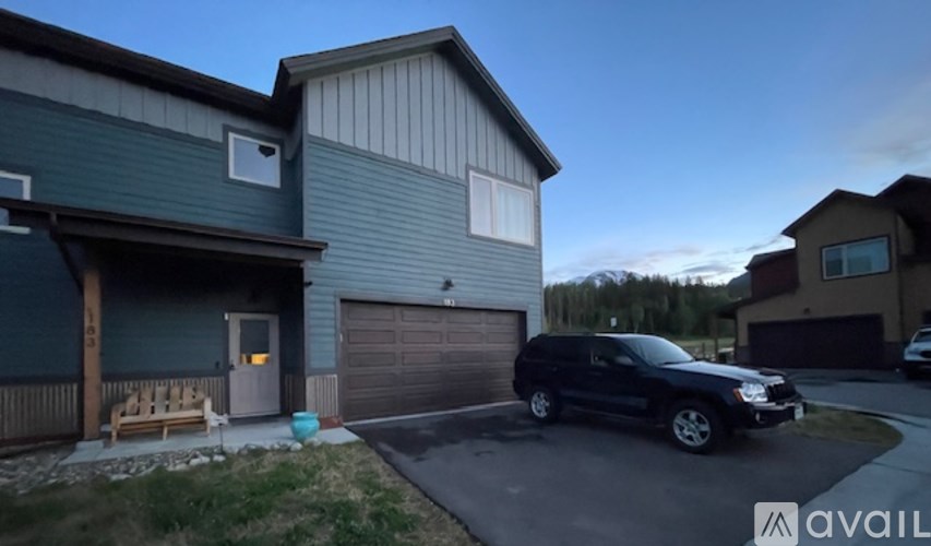 A black SUV is parked in front of a house with a garage.