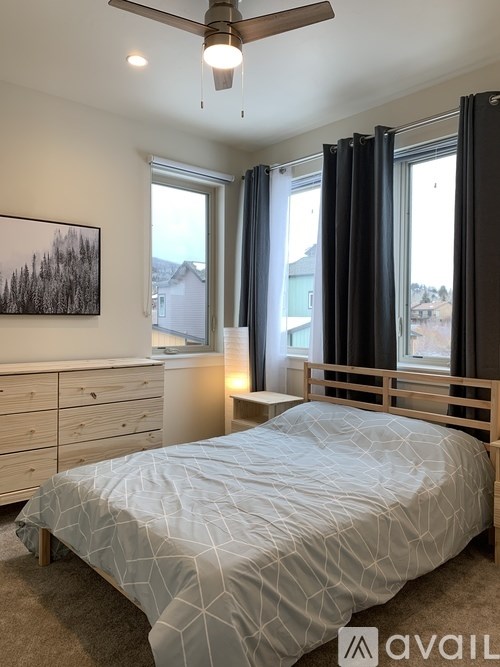 A bedroom with a bed, dresser, and window with black curtains.