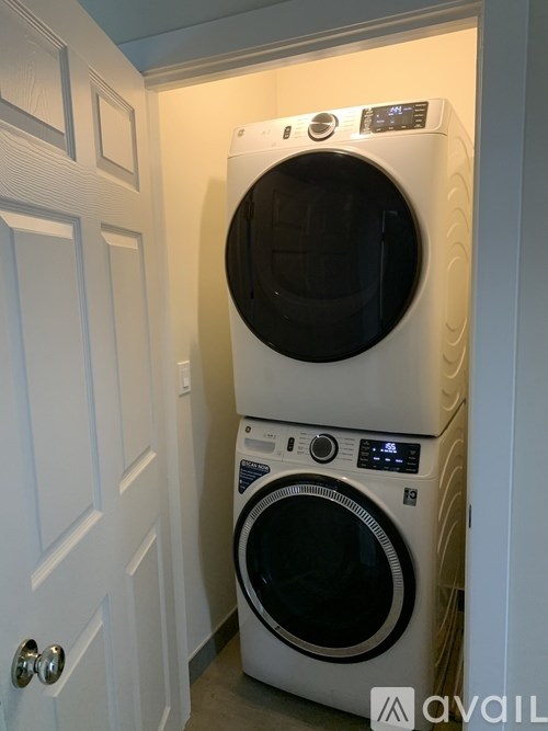A white washing machine and dryer stacked on top of each other in a small room.