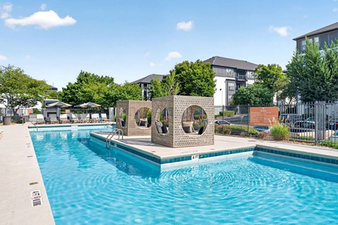 A pool with a blue tinted water and a sculpture in the middle.
