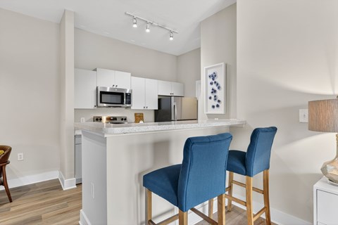 A kitchen with a white counter and blue chairs.